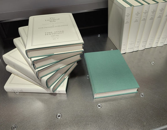 Volumes of The Liturgical Year stacked in cream dust-jackets, with the green cloth binding shown unjacketed, Saint Austin Press edition