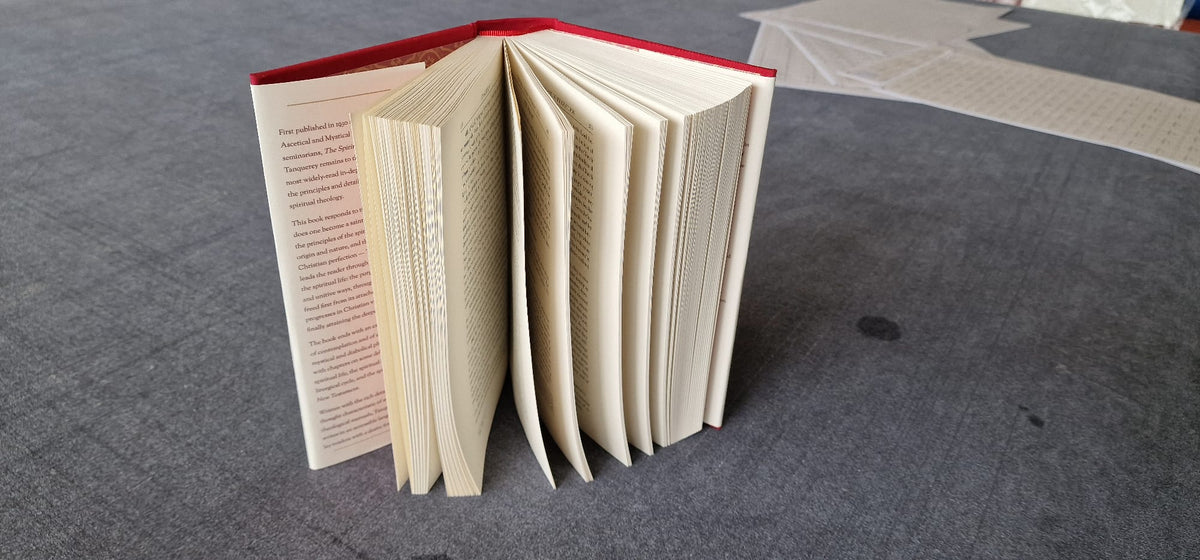 The Spiritual Life standing with pages fanned, showing the sewn binding and red cloth